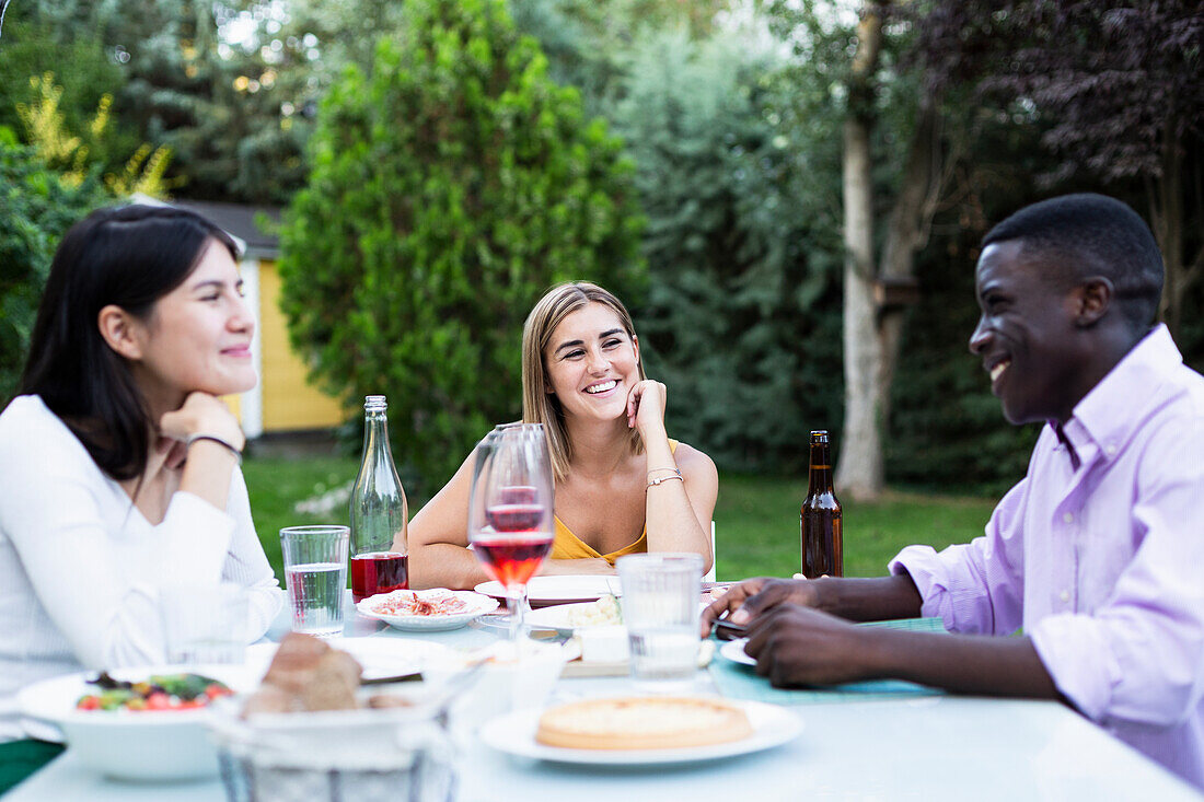 Freunde amüsieren sich bei einem sommerlichen Abendessen im Garten