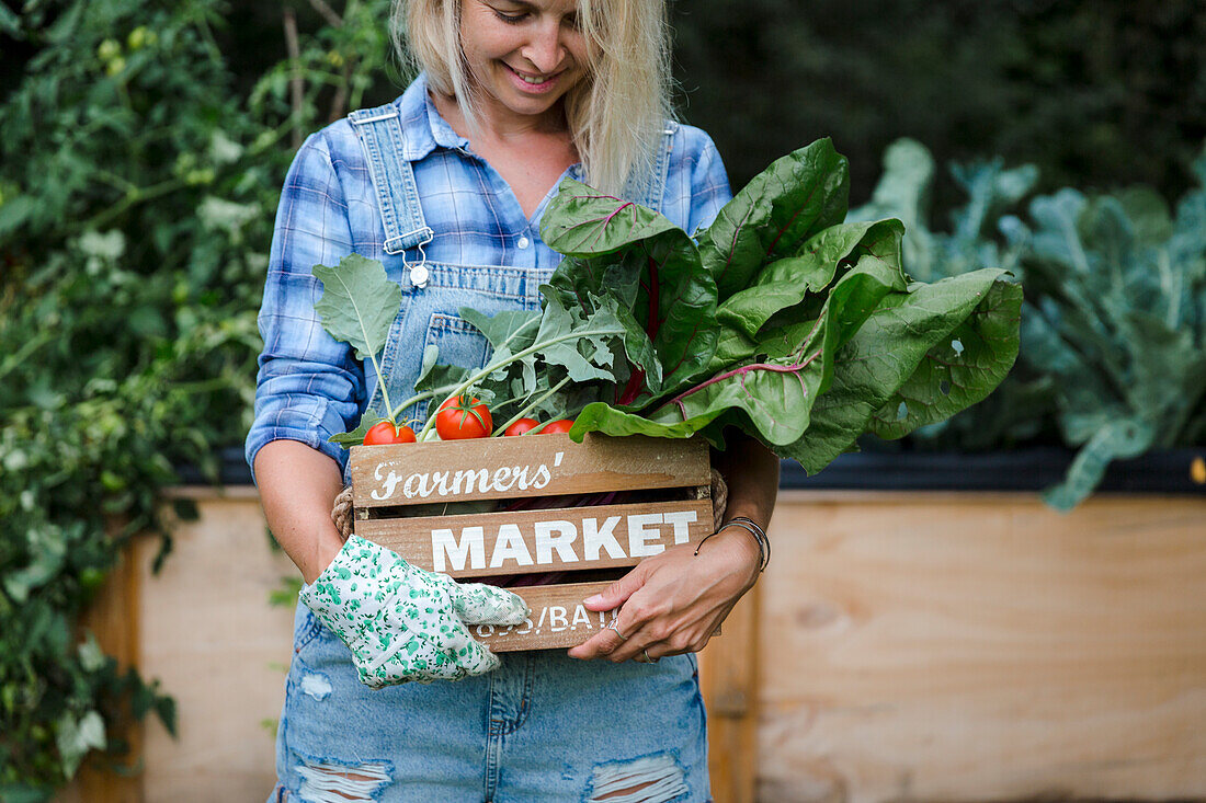 Blond smiling woman harvesting mangold