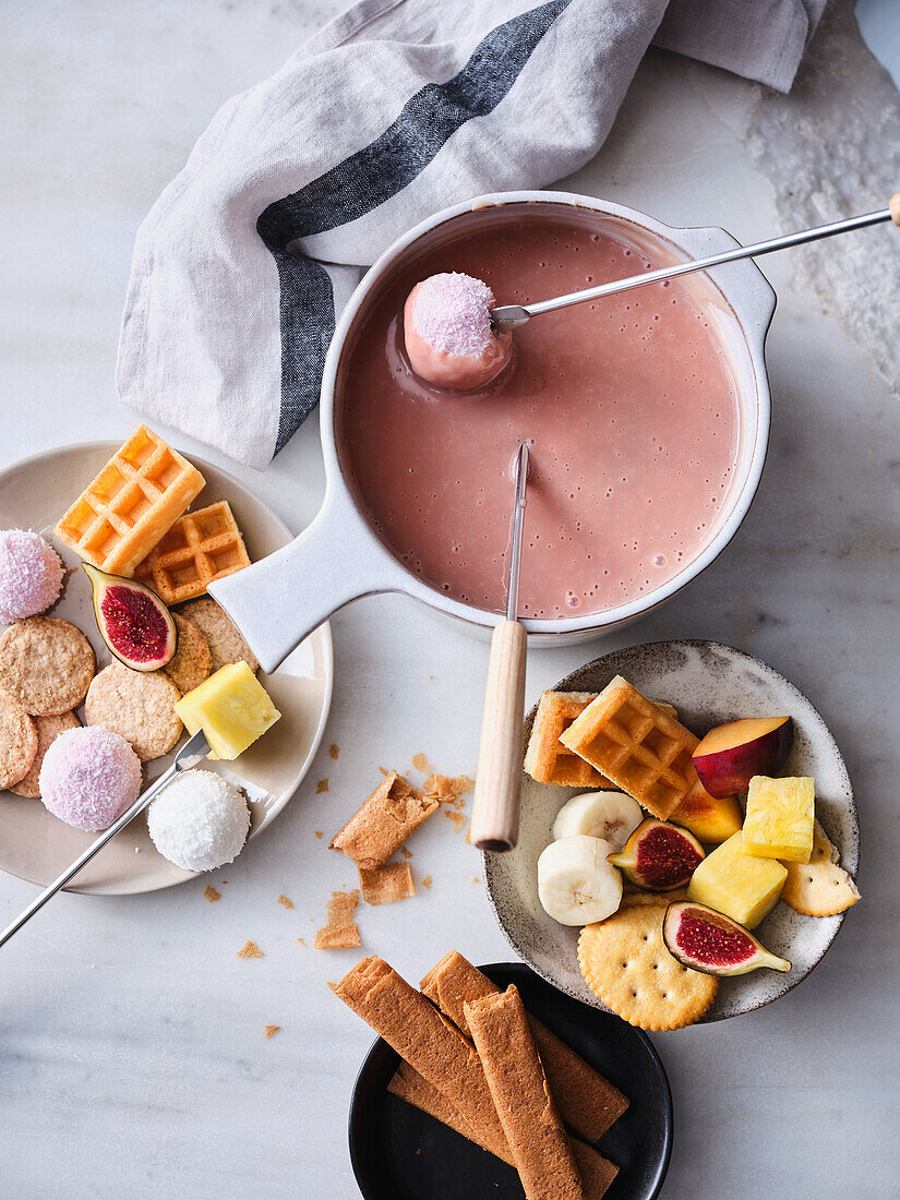 Rosa Ruby-Schokoladenfondue mit Früchten, Waffeln und Süßem