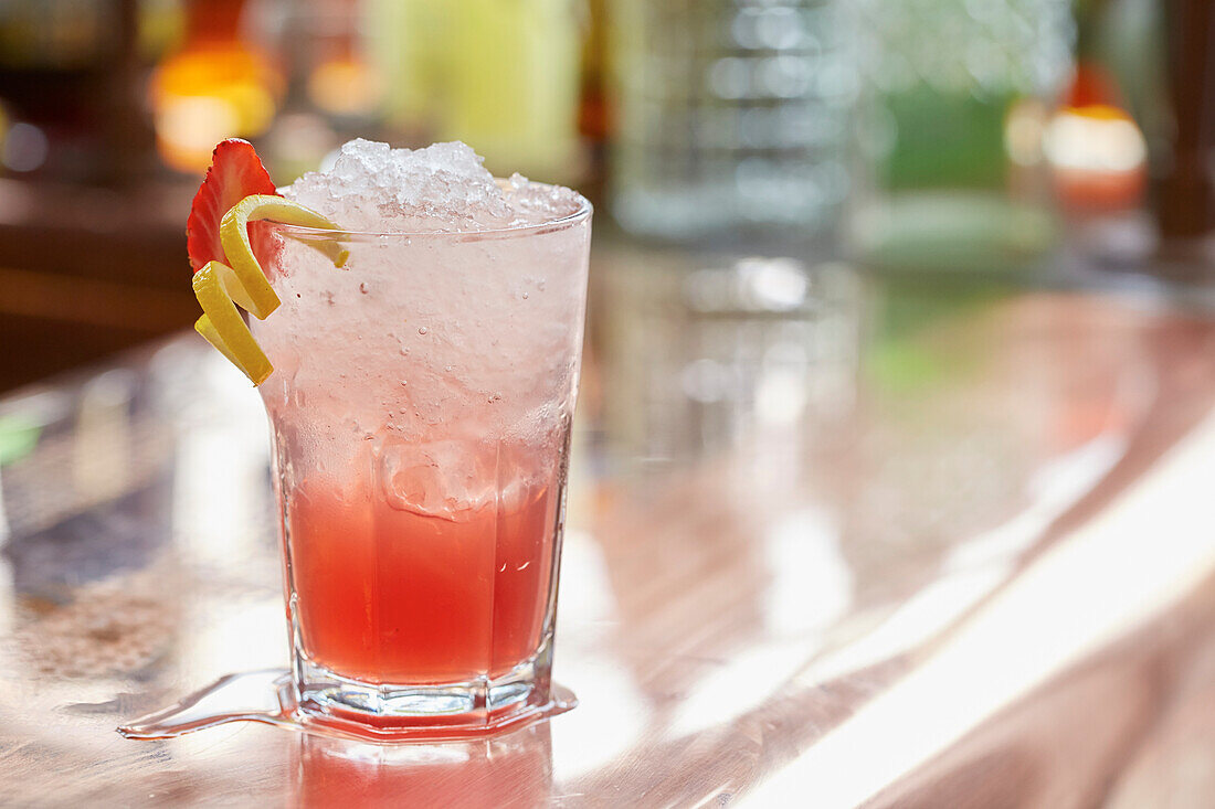 Roter Cocktail mit Crushed Ice, Erdbeer- und Zitronengarnierung