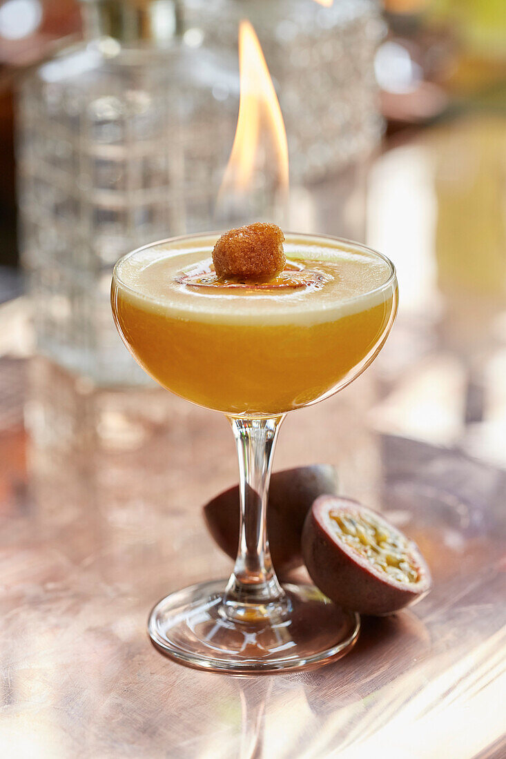 A passion fruit cocktail with flaming sugar cube