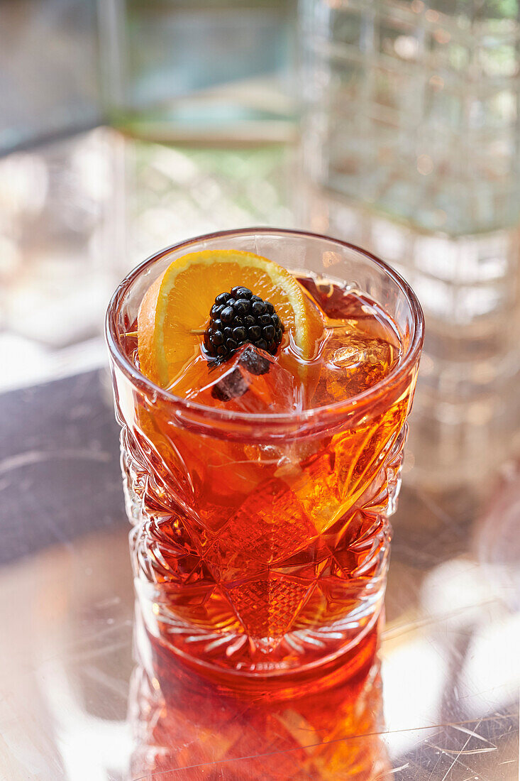 A Negroni, garnished with orange and blackberry