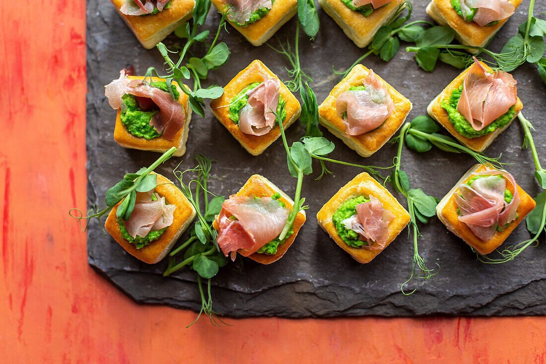 Puff pastry bites with Parma ham, pea puree, and pea shoots