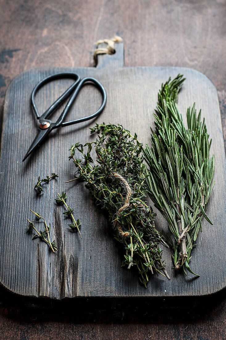 Rosemary and thyme with herb scissors on a wooden cutting board