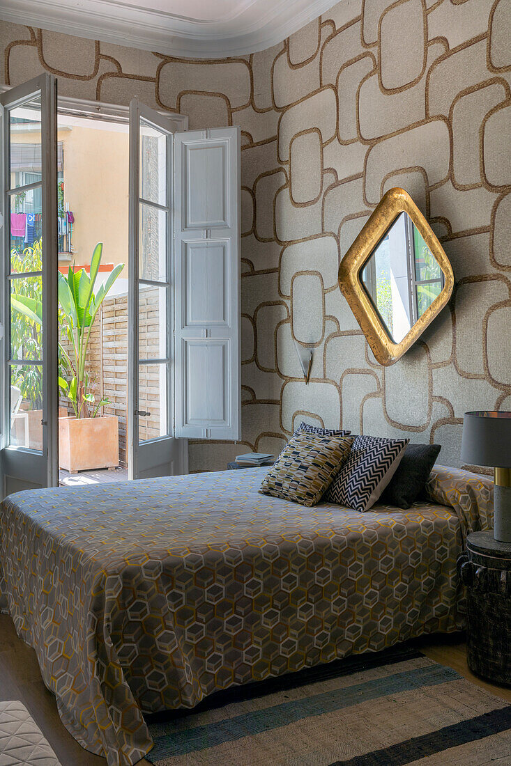 Queen bed and gold-framed mirror on wall with patterned wallpaper, in bedroom with access to the terrace