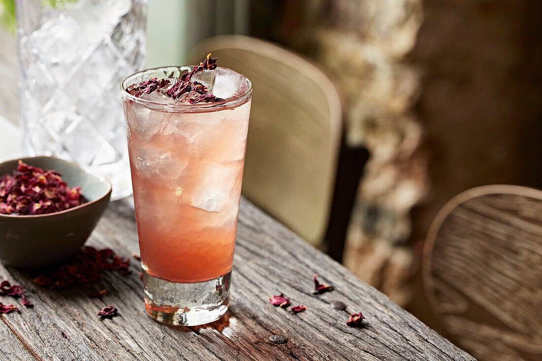Red pomegranate cocktail garnished with dried rose petals