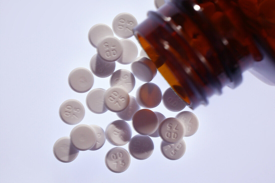Aspirin tablets spilling from an open bottle