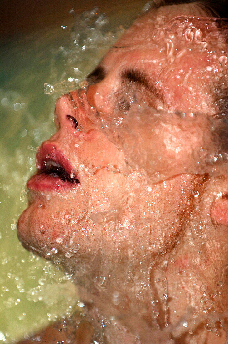 Water splashing on young man's face