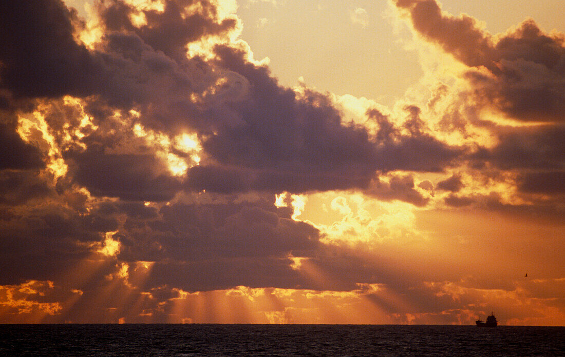 Sunset behind clouds over sea