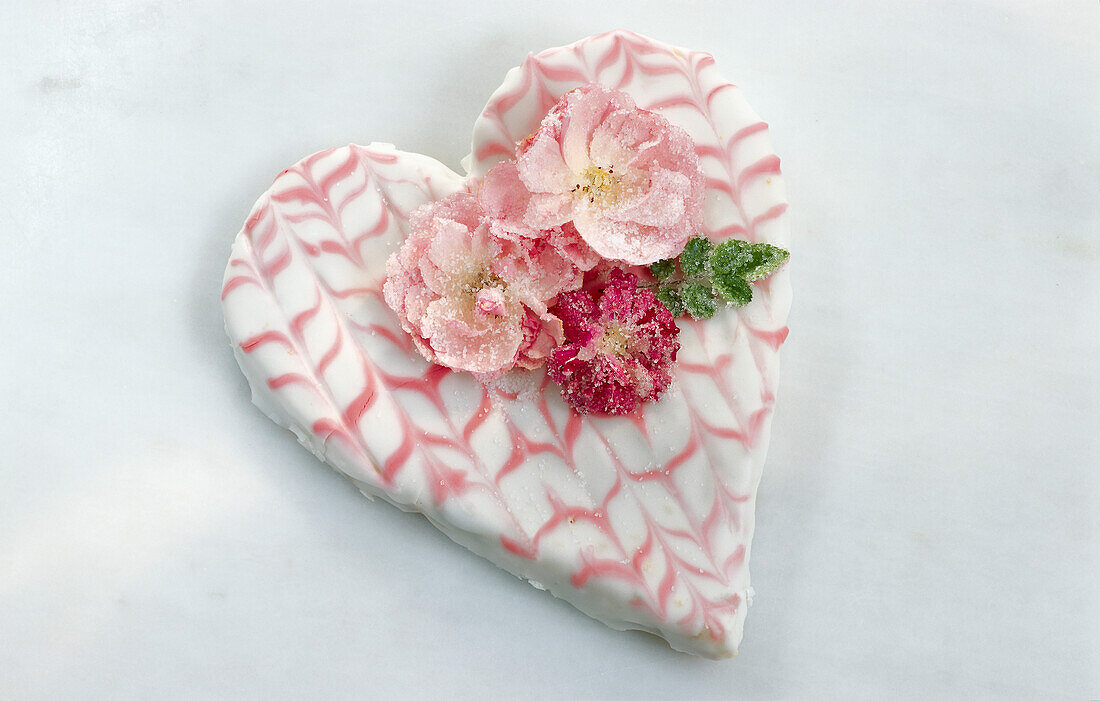 Herzförmige Torte zum Valentinstag, mit gezuckerten Rosenblüten