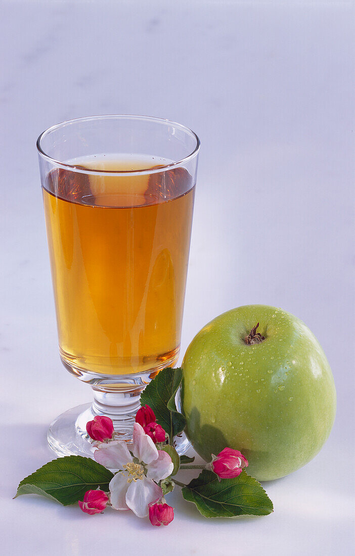 Glas Apfelsaft, ein Apfel und Apfelblüte