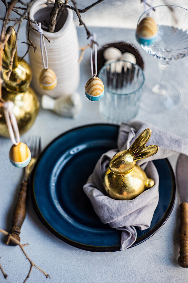 Gedeck mit goldenen Osterhäschen, Zweige mit Ostereiern