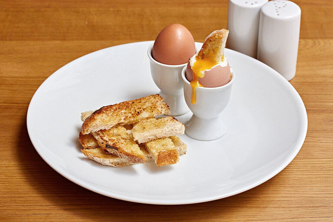 Boiled eggs and toast soldiers, one yolk with a dipped piece of toast