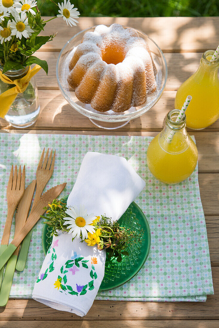 Laid garden table with cake and fresh lemonade in summer