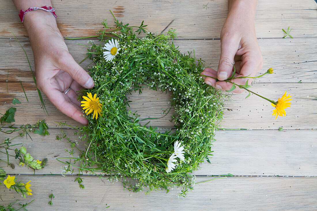 DIY wreath of fresh meadow flowers on wooden table