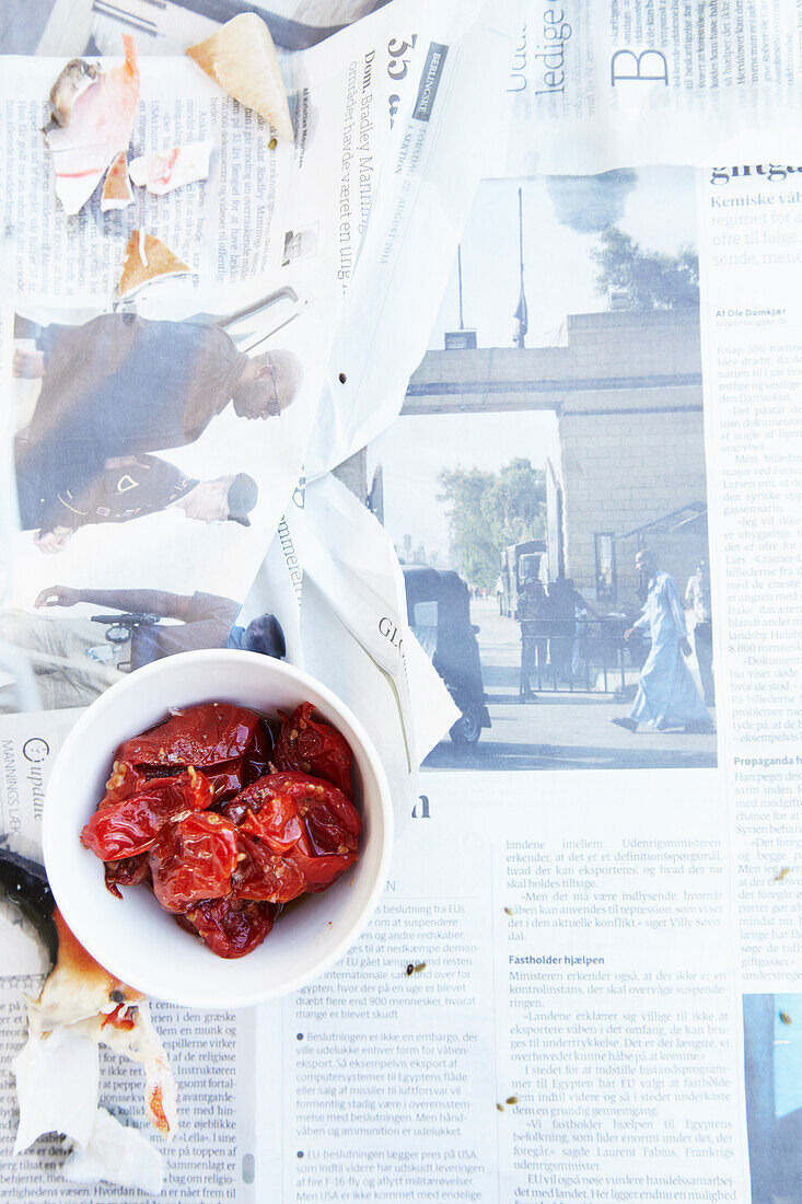 Tomato confit in a small bowl on newspaper