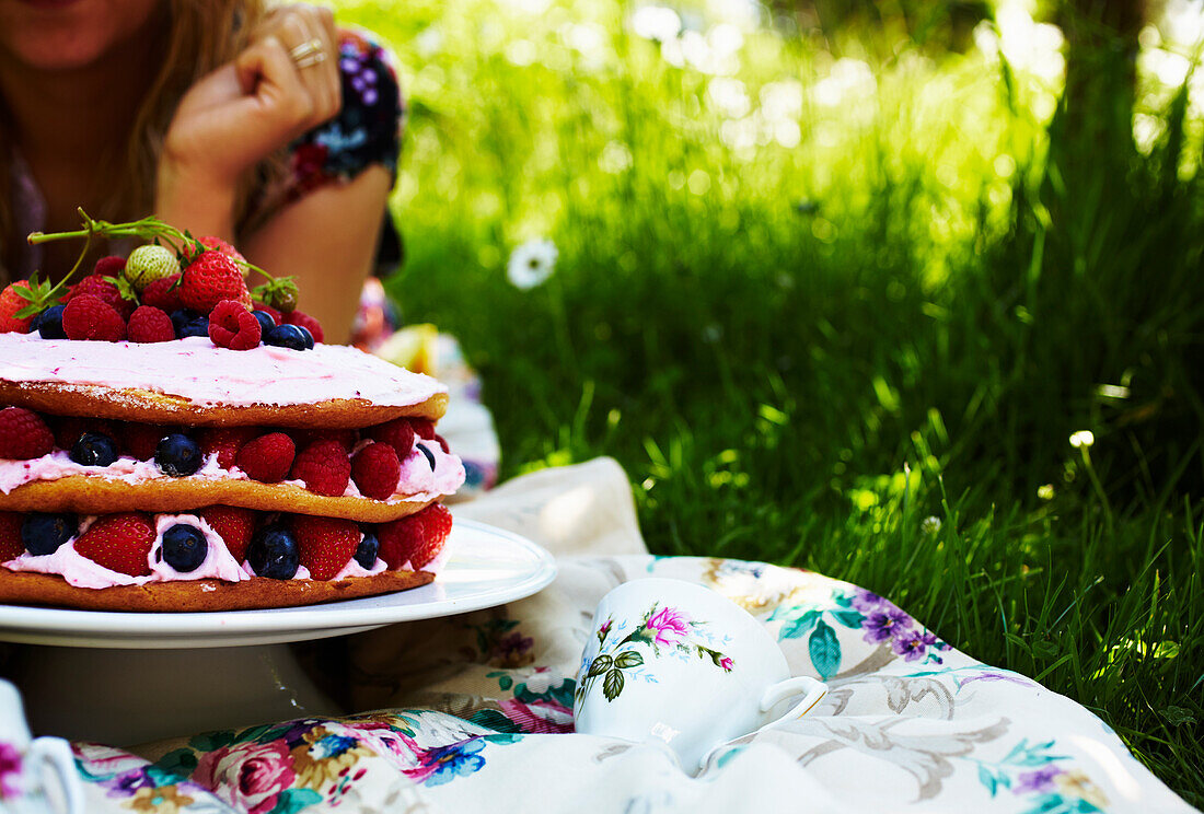 Schichtkuchen mit Himbeermousse und frischen Beeren auf Tisch im Garten