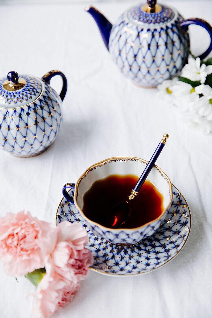 Eine Tasse Schwarztee, Nelken und dekorative Teekanne auf gedecktem Tisch