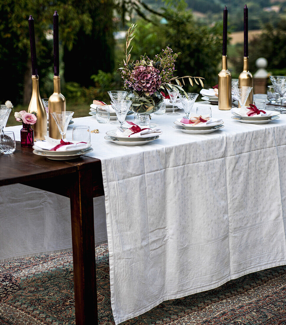 Festively set garden table with a bouquet of flowers and golden candlesticks