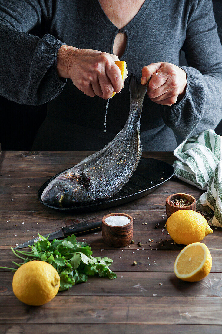 Woman chef preparing a fresh fish dorado by cutting