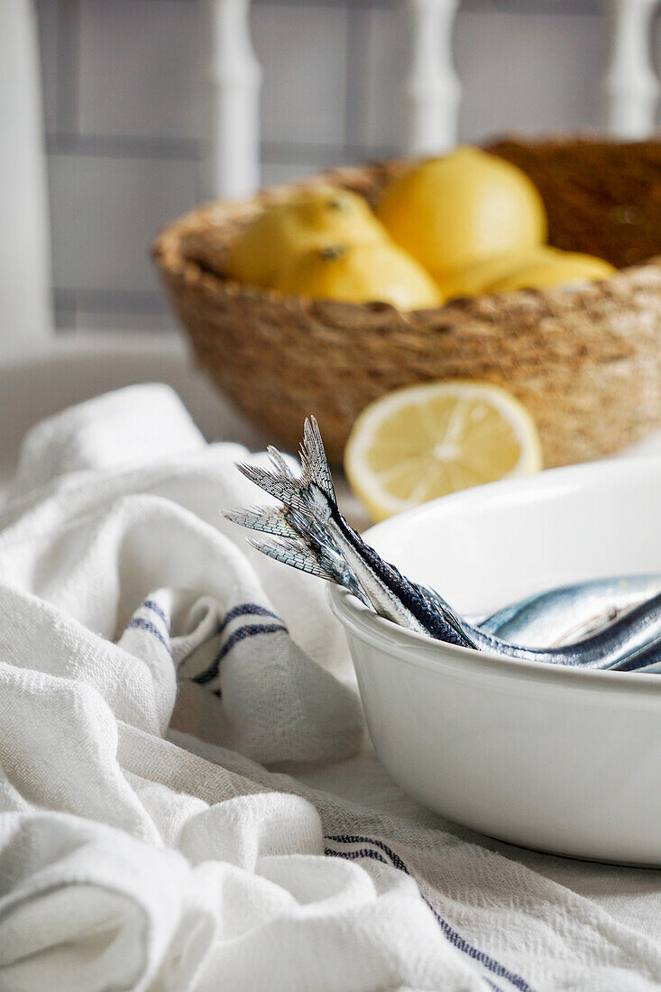 Frische Sardinen in einer Schale daneben Leinentuch  und Zitronen