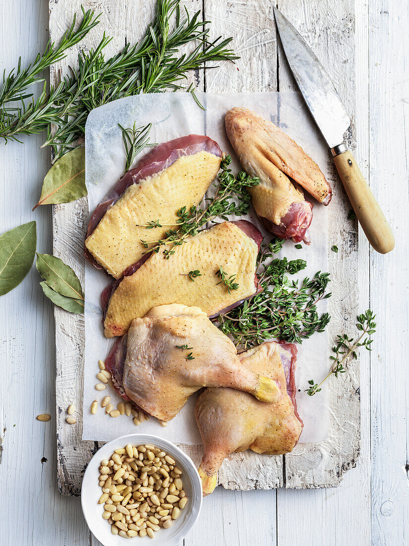 Raw duck parts with herbs and pine nuts on a cutting board