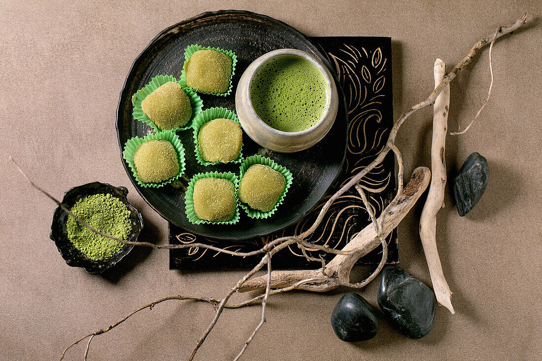 Asian rice dessert sweet green matcha mochi with cup of frothed matcha tea. Flat lay