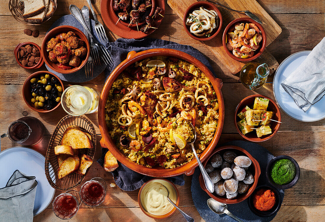 Spanish paella in a baking dish surrounded by tapas in bowls