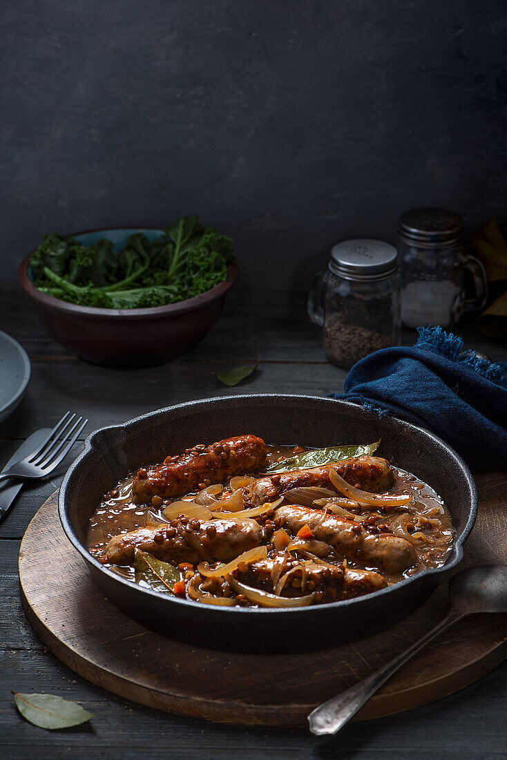 Sausages with onion and lentil gravy in a pan