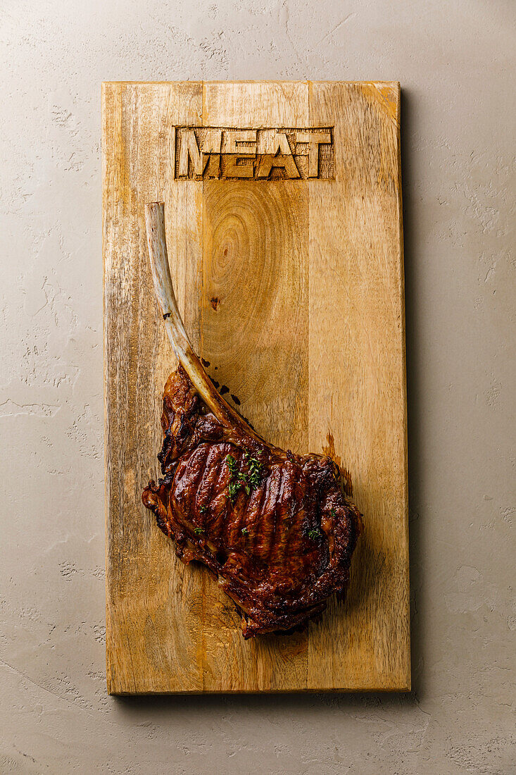 Barbecue grilled Tomahawk Steak on bone on wood serving board