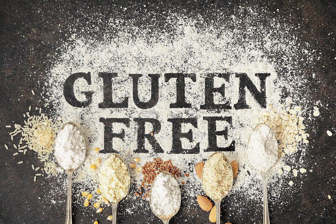 Gluten free written in flour on vintage baking sheet and spoons of various gluten free flour