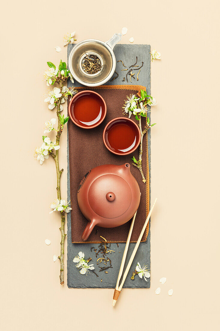 Asian Tea set on stone slate board, ceramic teapot, cups, dried tea and spring branches, tea ceremony