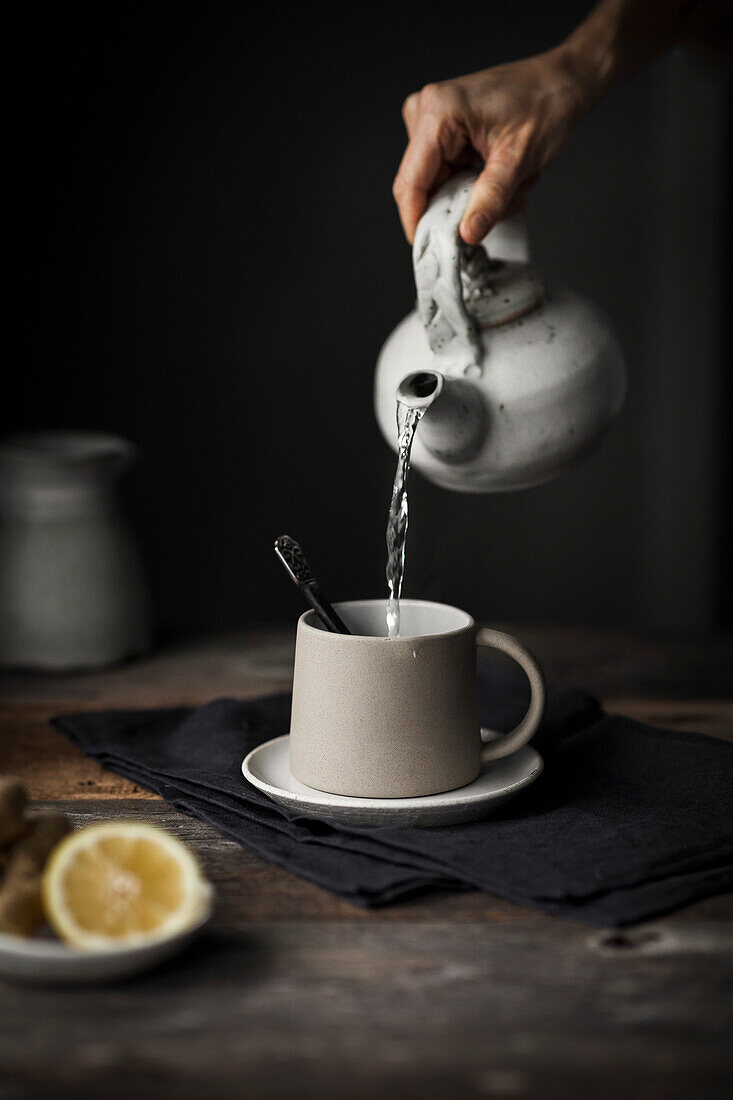 A person pouring hot water into a tea mug with lemon