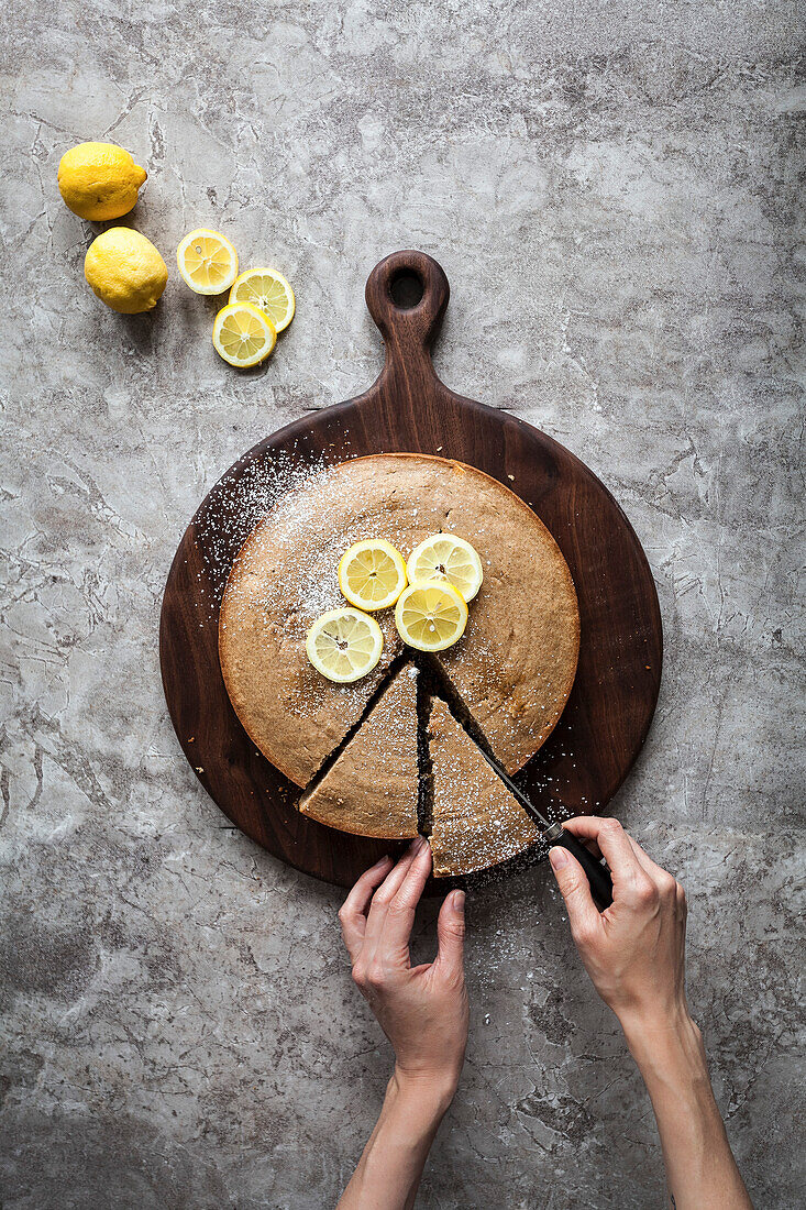 A person slicing into a lemon cake