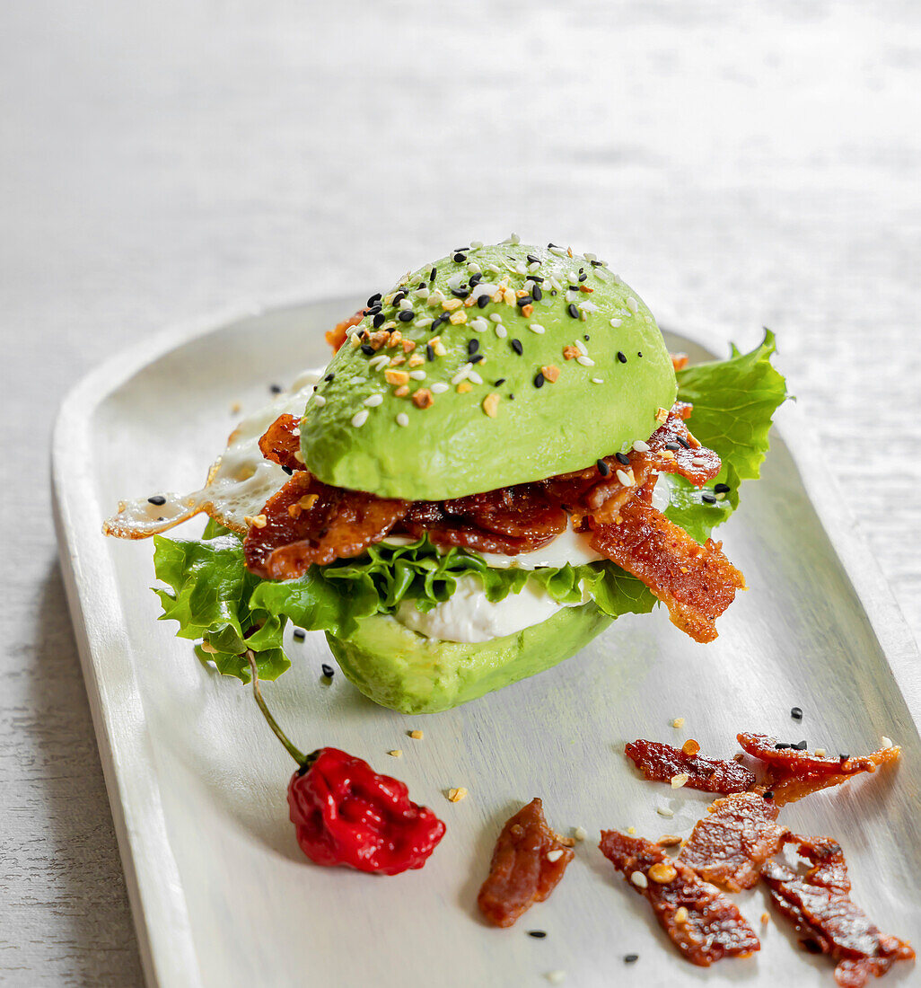 Avocado burger with bacon on a grey plate