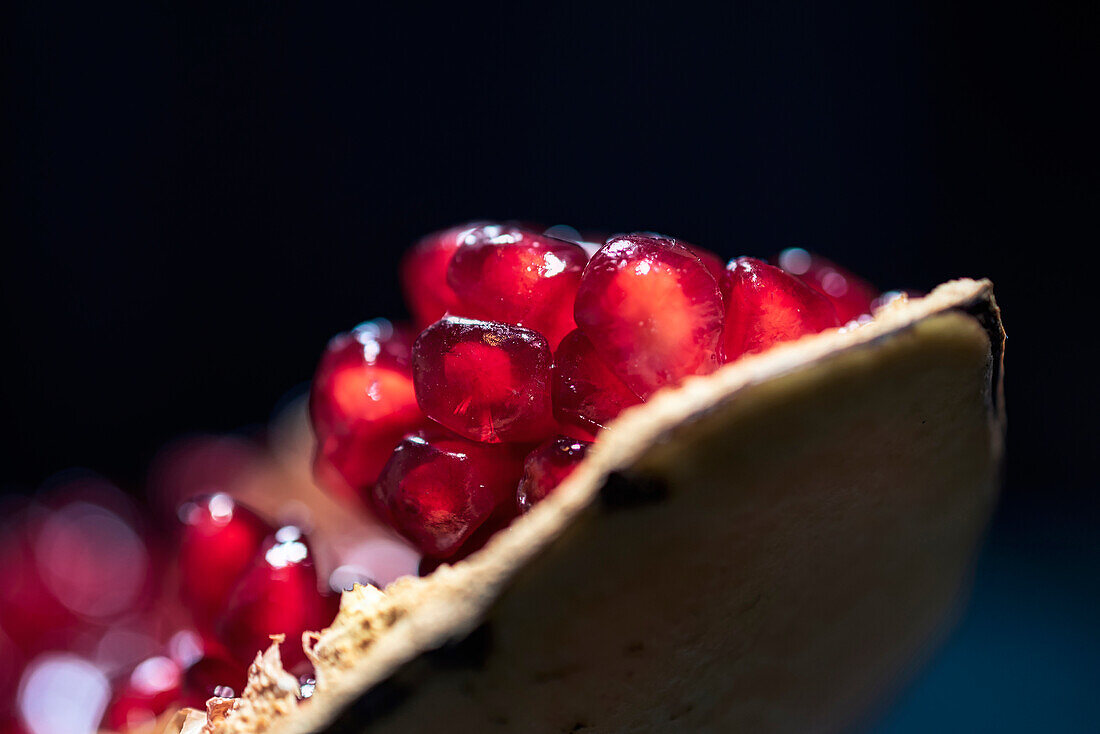 Ripe peeled red pomegranate with juicy fresh fruits placed on wooden black surface