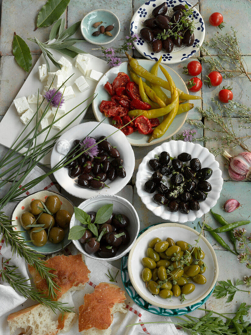 Stilleben mit verschiedenen Oliven, getrockneten Tomaten, eingelegter Chili, Schafskäse