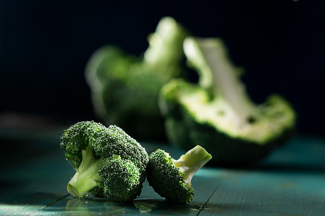 Broccoli florets, with whole and half broccoli in the background