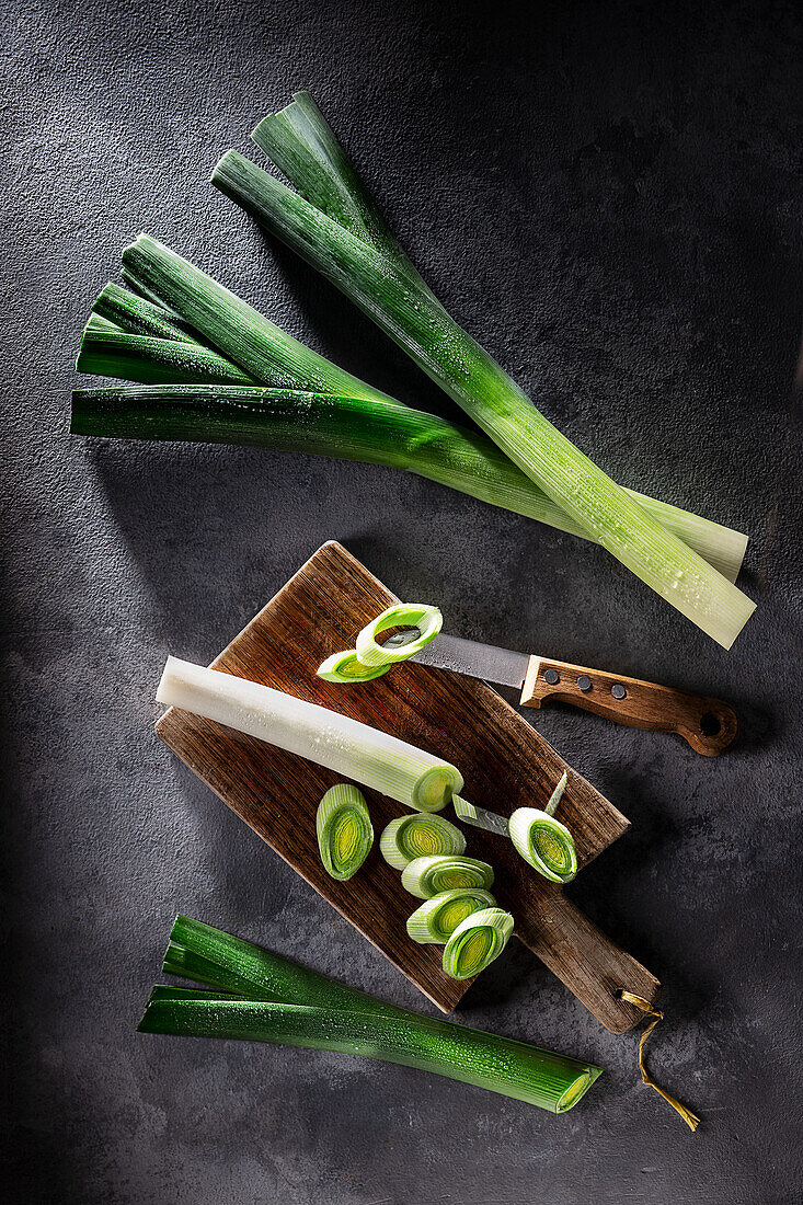 Leeks, whole and cut on wooden board