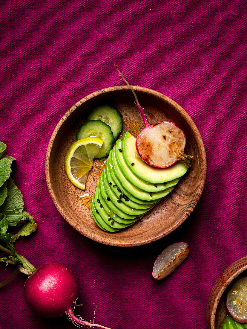 Fresh avocado and radish on plate with cucumbers, lime and chia seeds