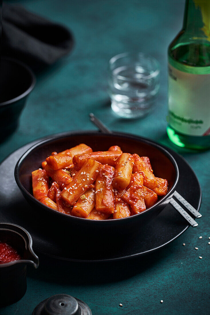 Pile of stir fried spicy rice cakes tteokbokki topped with sesame seeds