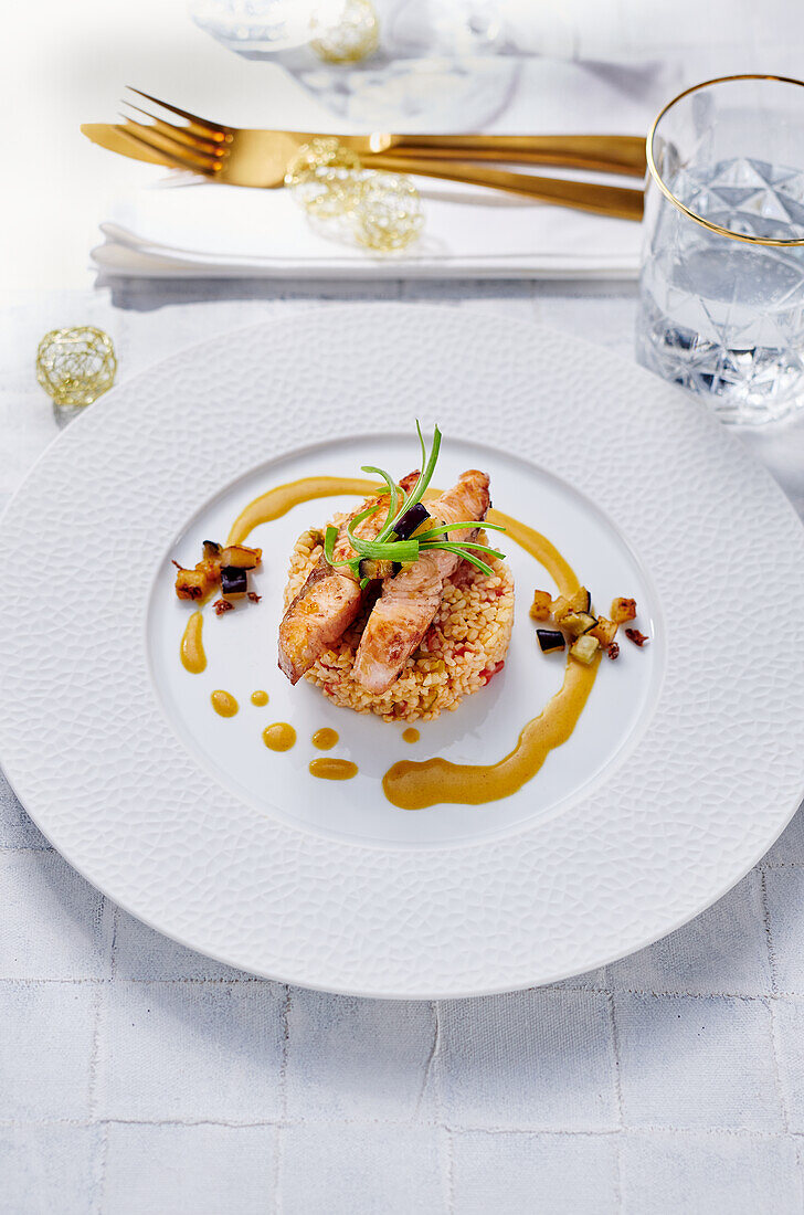 Salmon strips on bulgur on a festive white plate with golden accents