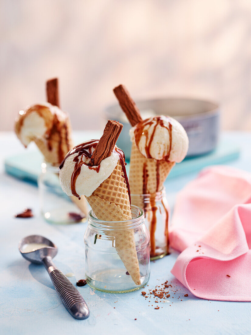 Vanilleeis mit Schokoladensauce und Schokoladenröllchen in Eistüten