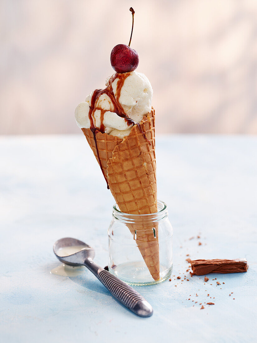 Vanilla ice cream with waffle cone and chocolate sauce and cherry
