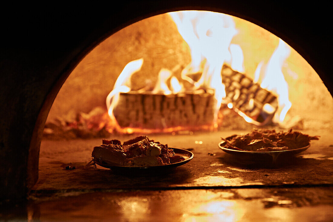 Zwei Teller mit Gerichten in einem Holzofen mit Feuer