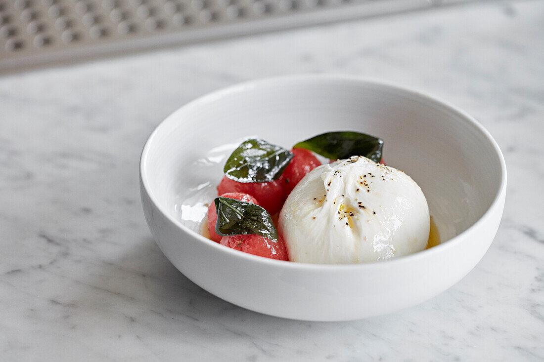 Burrata mit Wassermelonenbällchen, beträufelt mit Olivenöl