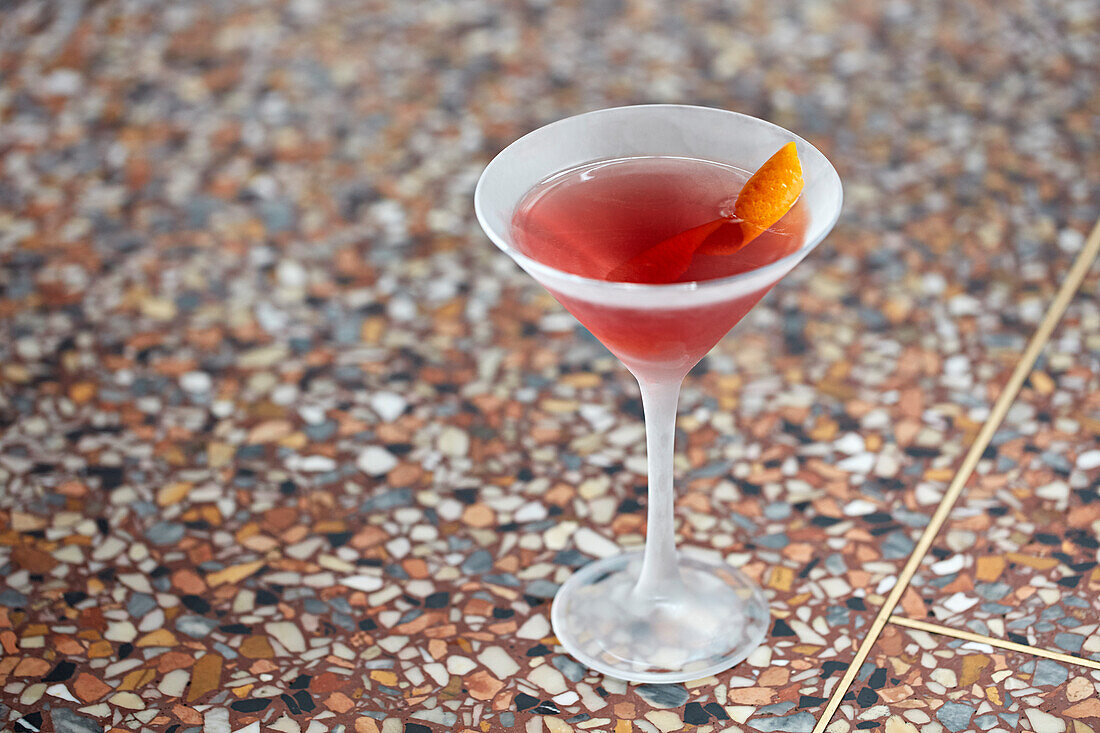 An elegant cocktail with an orange garnish