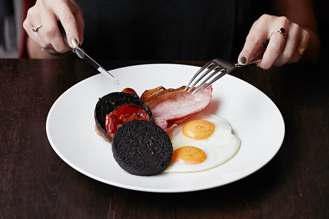 Englisches Frühstück mit Spiegeleiern, Blutwurst und Speck