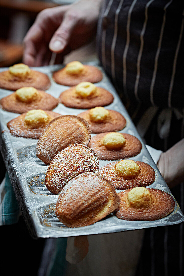 Tray of a dozen Madelines held by a chef