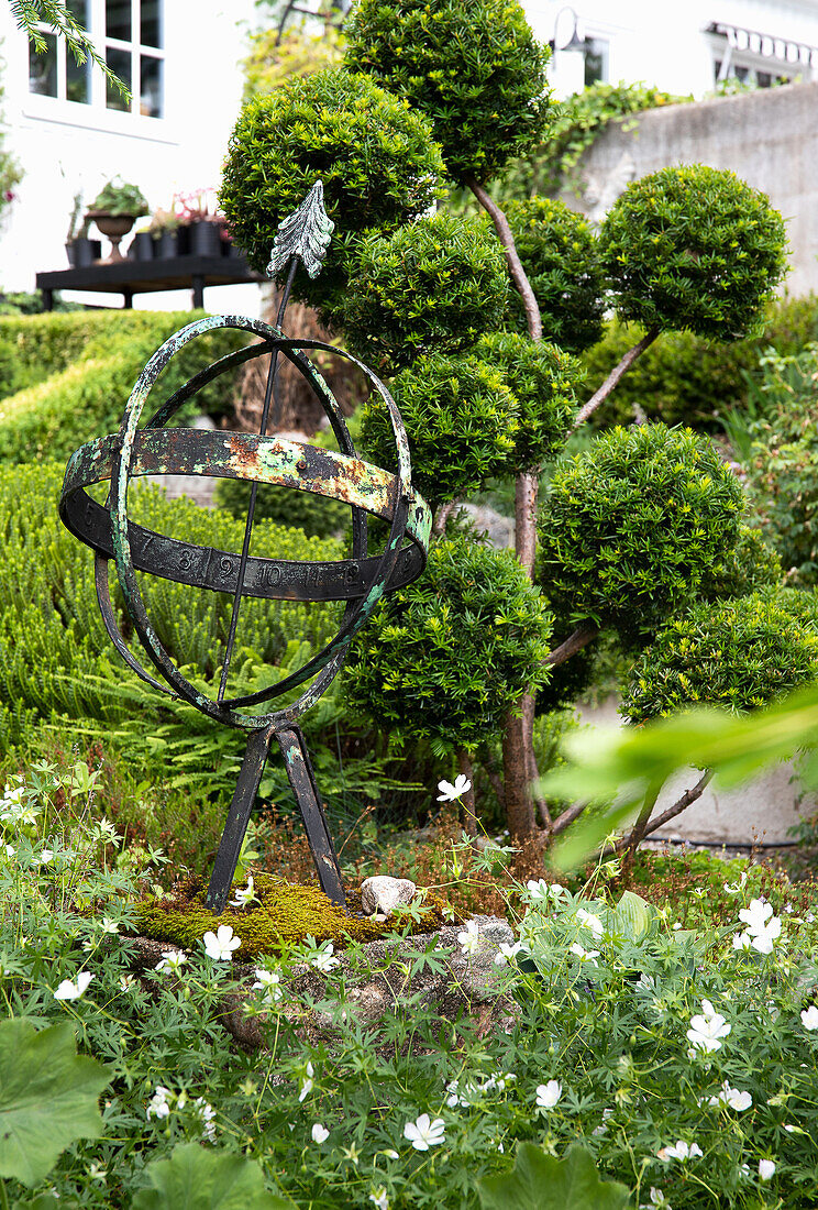 Bepflanztes Gartenbeet mit Armillarsphäre und japanischer Eibe